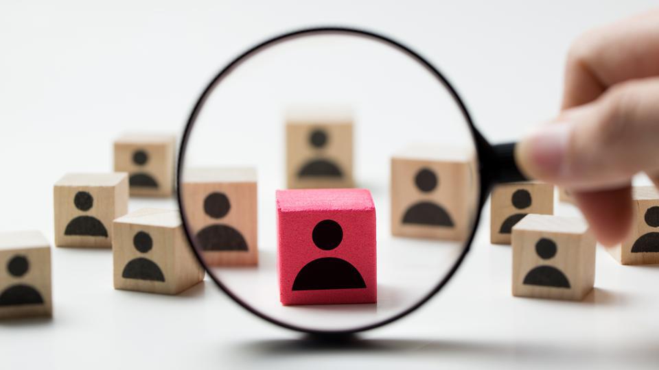 Scattered wood blocks with magnifying glass circling one red block in center